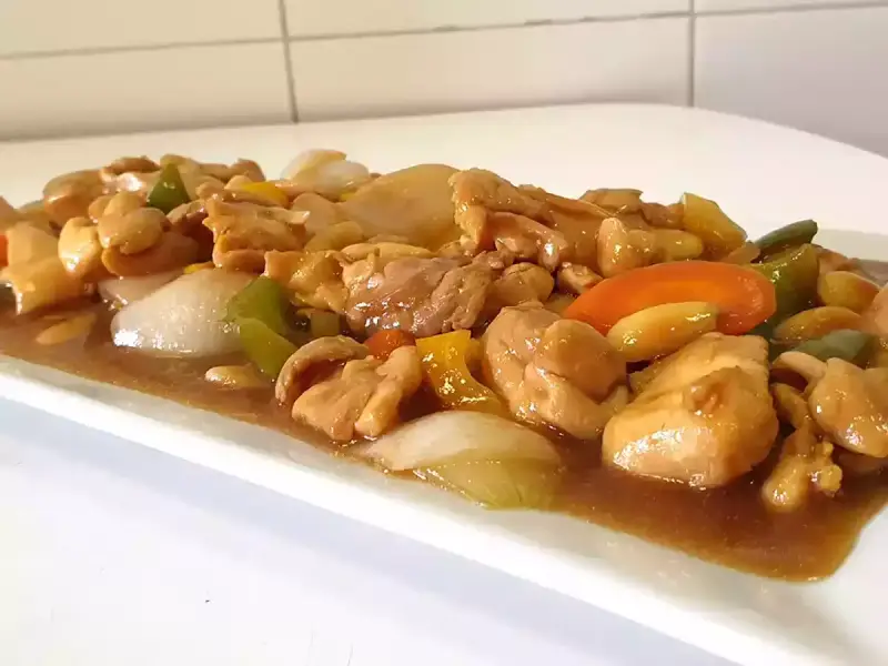 Delicioso pollo con almendras, pimientos y cebolla en una salsa dorada.